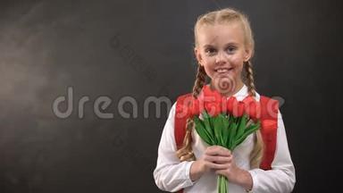 漂亮的女<strong>一年级</strong>学生拿着郁金香花束在黑板上